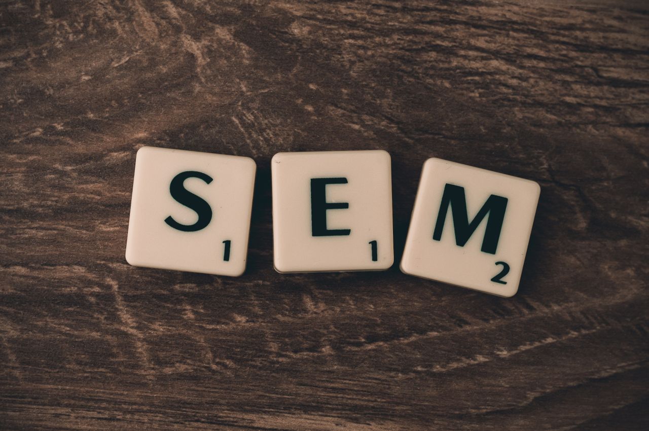A wooden backdrop with letter tiles arranged to spell SEM, evoking search engine marketing.